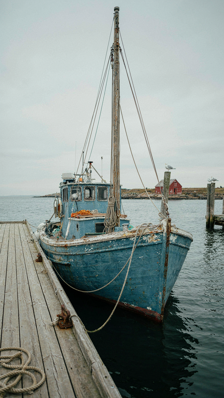 A weathered fishing boat tied to a simple wooden dock.