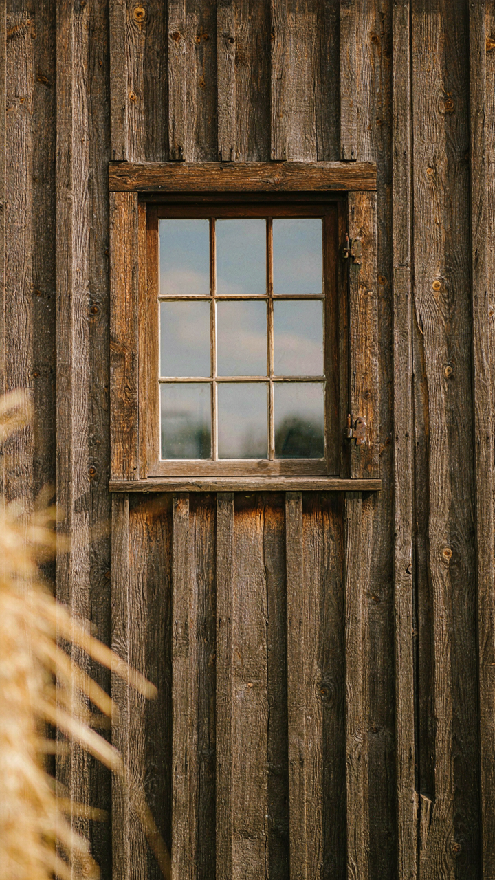 A historic, overbuilt barn window with thick wooden frames in a timber wall.