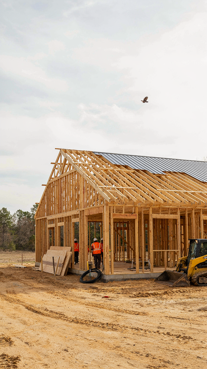 A large, open barn style home shell under construction with exposed posts and beams.