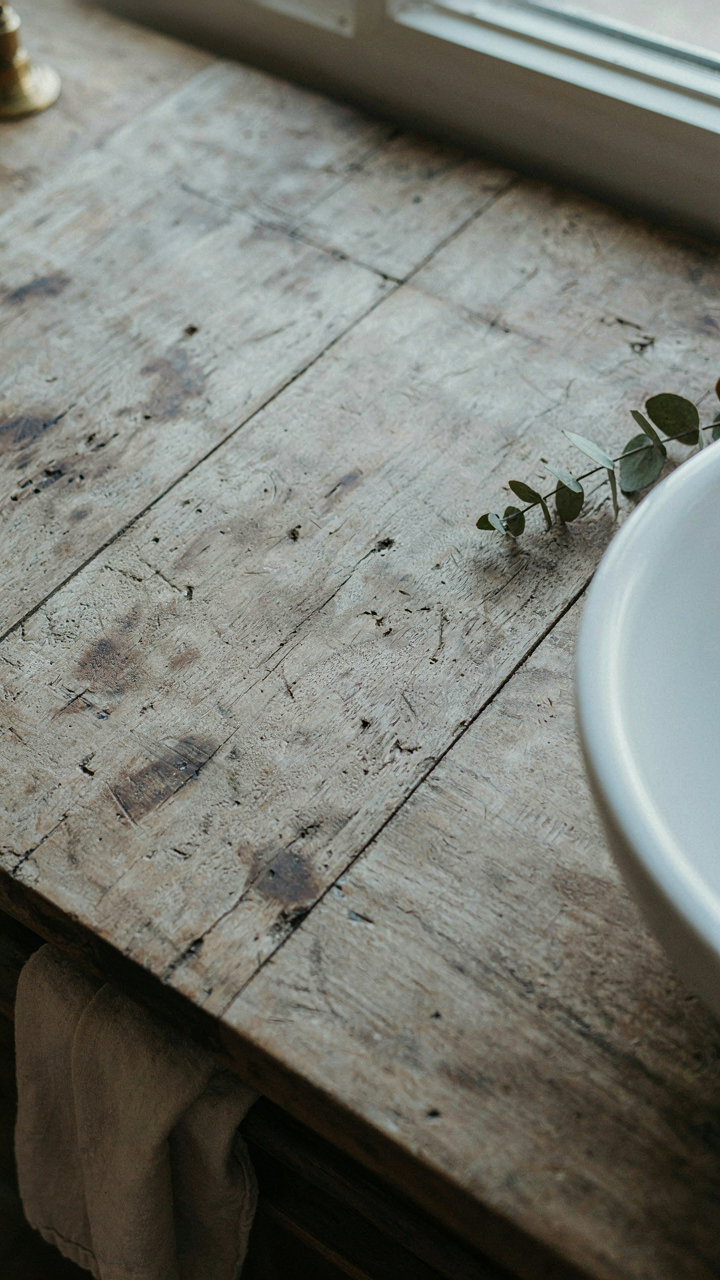 A reclaimed wood vanity top shows visible water stains and natural imperfections.