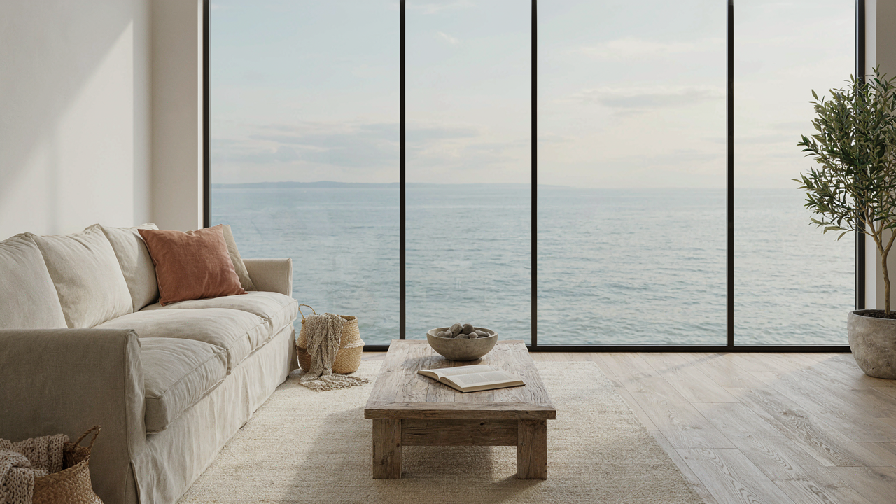 A bright coastal living room with neutral colors and a view of the ocean.
