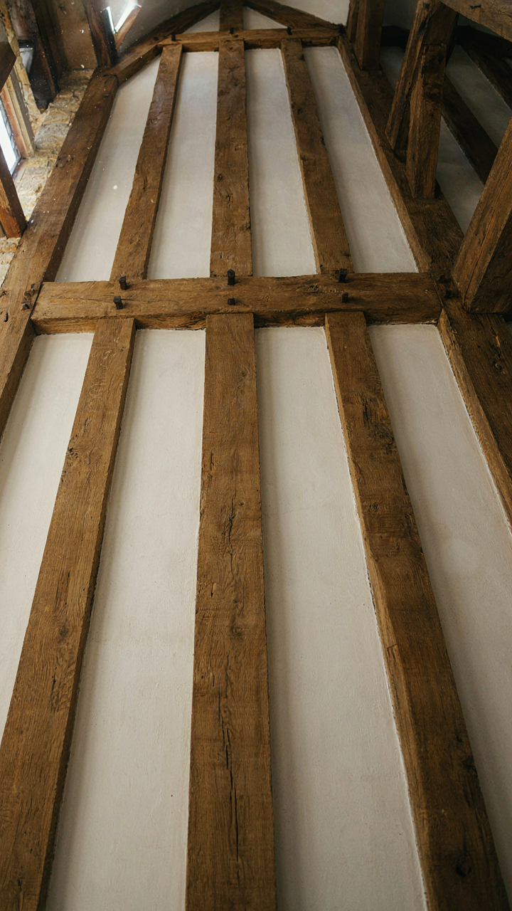 Heavy oak timber beams support a ceiling with white plaster infill.
