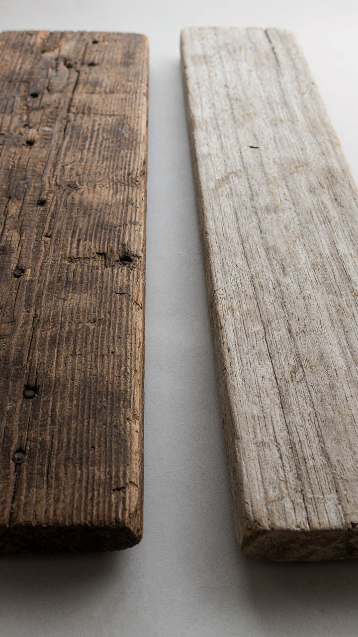 Two contrasting wood samples, dark reclaimed barn wood and light driftwood, side by side.