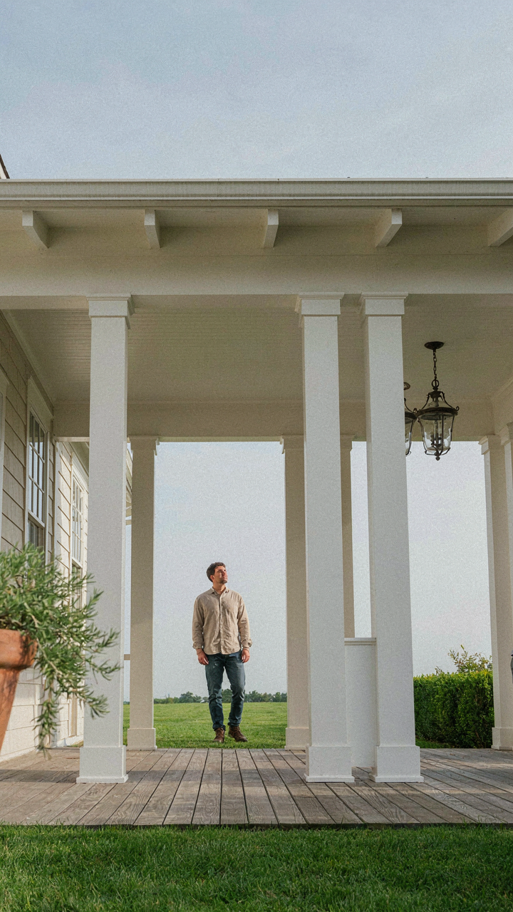 Person stands back observing the balanced proportions and tapered columns of a craftsman porch.