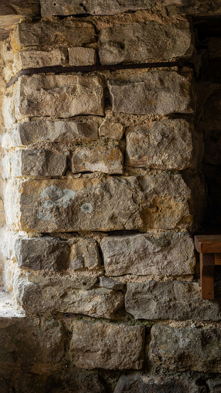 A raw, exposed stone wall in a cottage, showing its structural integrity.