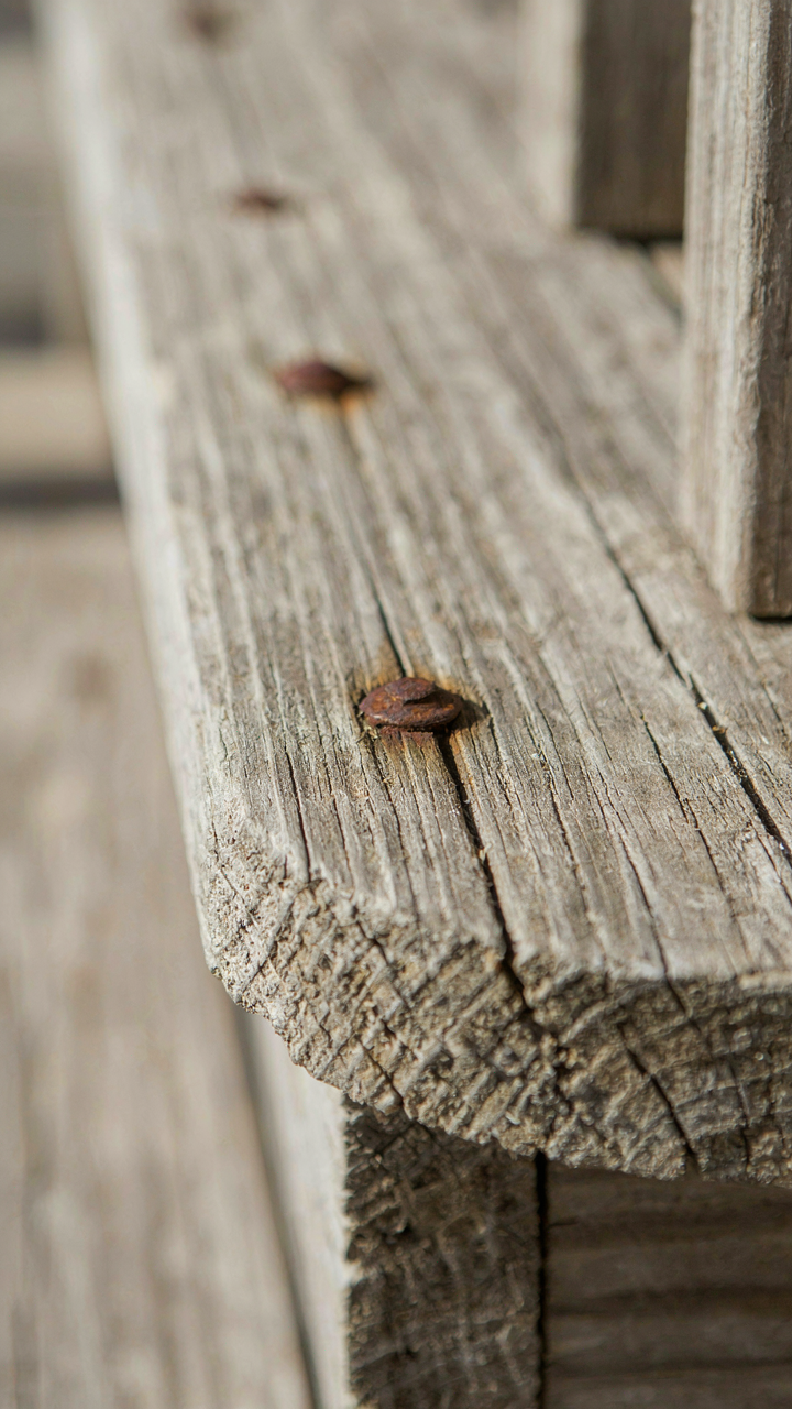 Weathered cedar porch step with visible wood grain and aging metal fasteners.