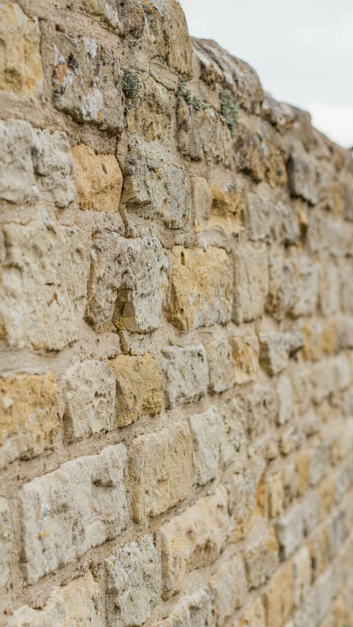 Weathered Cotswold stone masonry with visible lime mortar and lichen growth.