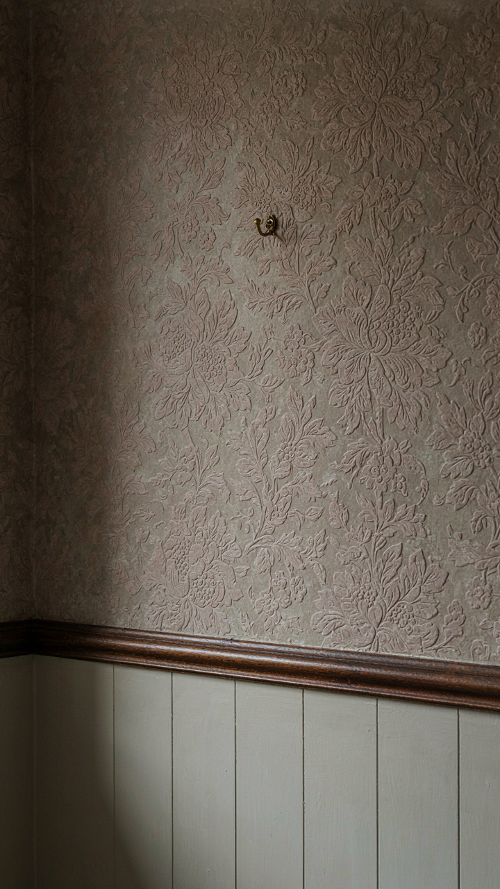 A Victorian wall with a dado rail, embossed floral wallpaper, and painted lower section.