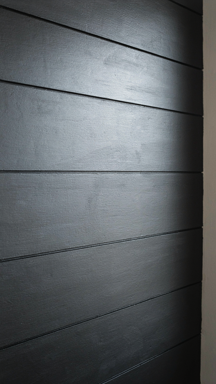 Close up of dark painted shiplap, showing deep shadow lines between boards.