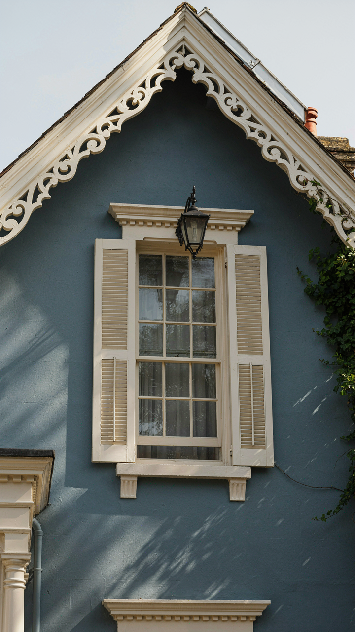 A Victorian house wall in slate blue with contrasting cream trim.