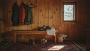 A warm and inviting cabin entryway with a wooden bench, coat hooks, and natural light.