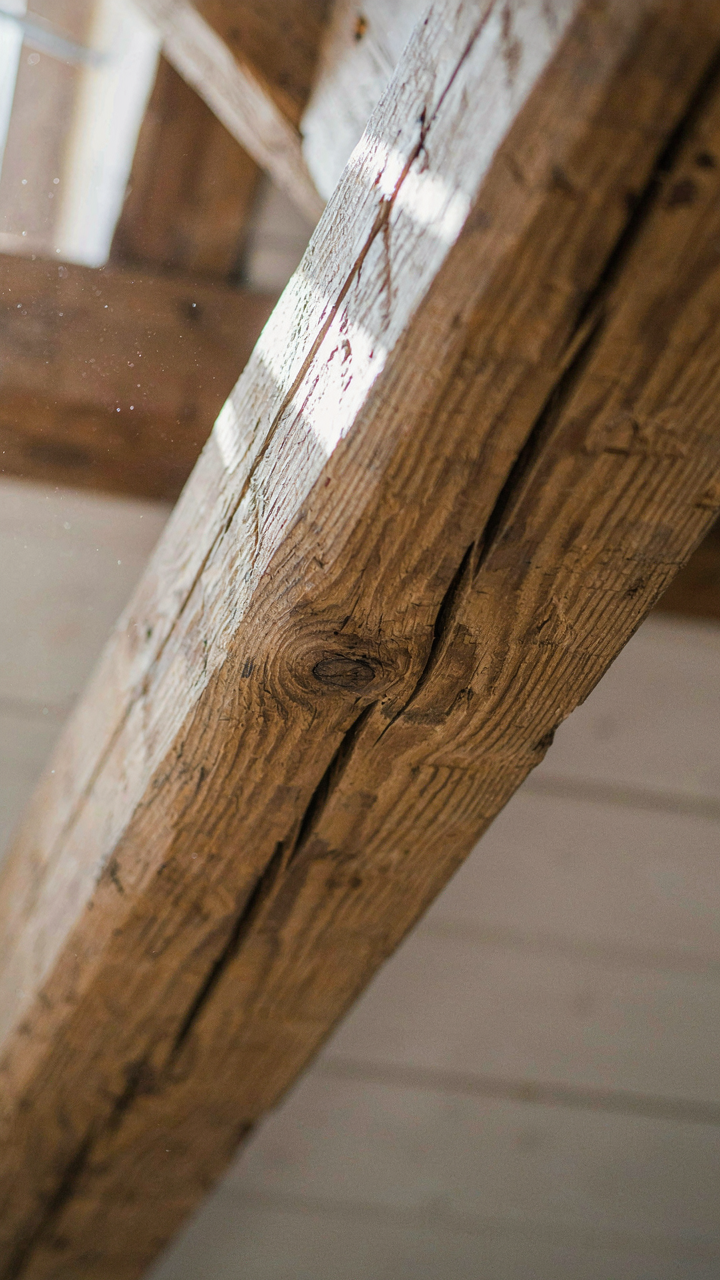 A close-up of a hand-hewn ceiling beam with visible chisel marks.