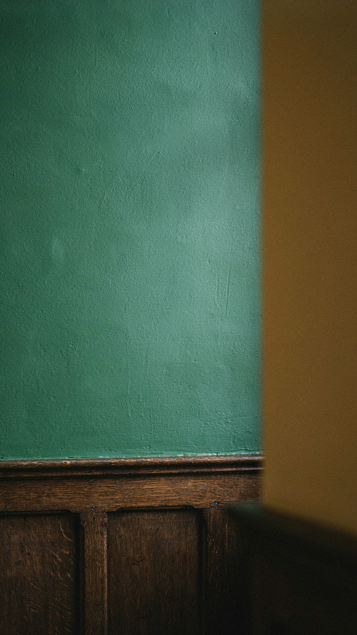 Dark wood paneling with forest green and ochre yellow walls in a Tudor room.