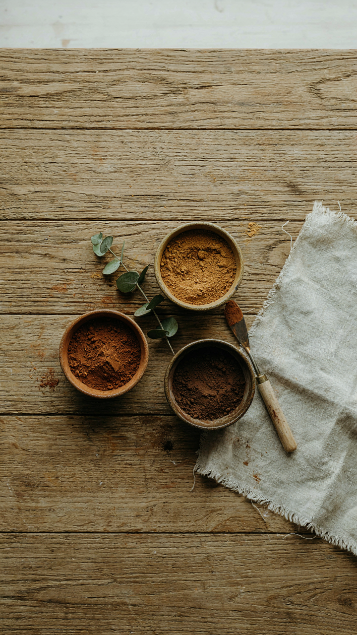 Bowls of deep ochre, burnt sienna, and charcoal brown pigments next to a fabric swatch.