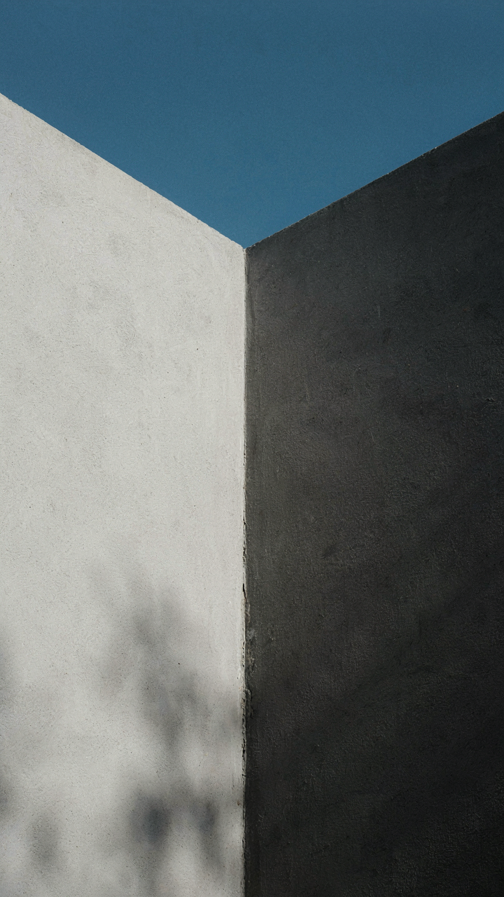 A pristine white wall reflecting bright sunlight, next to a dark gray wall.
