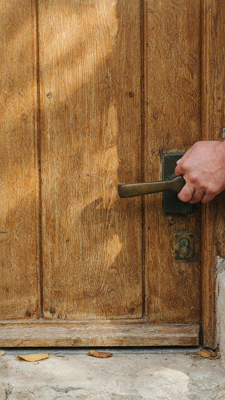 A hand reaching for a substantial, oil-rubbed bronze door handle.