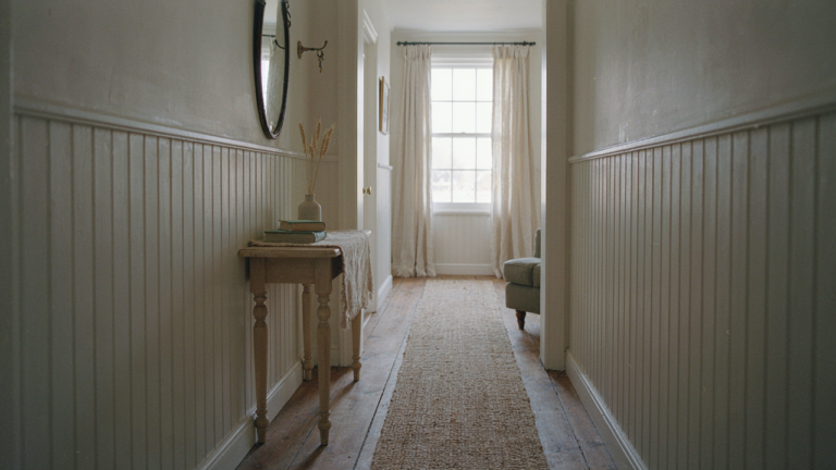 A charming cottage hallway with white beadboard walls and a small wooden console table.