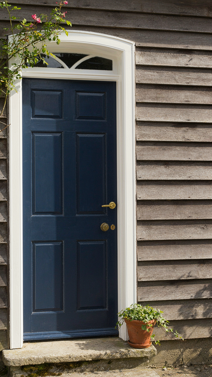 A deep navy cottage door framed by crisp white trim.