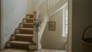 A rustic cottage staircase with worn wooden steps and a white railing.