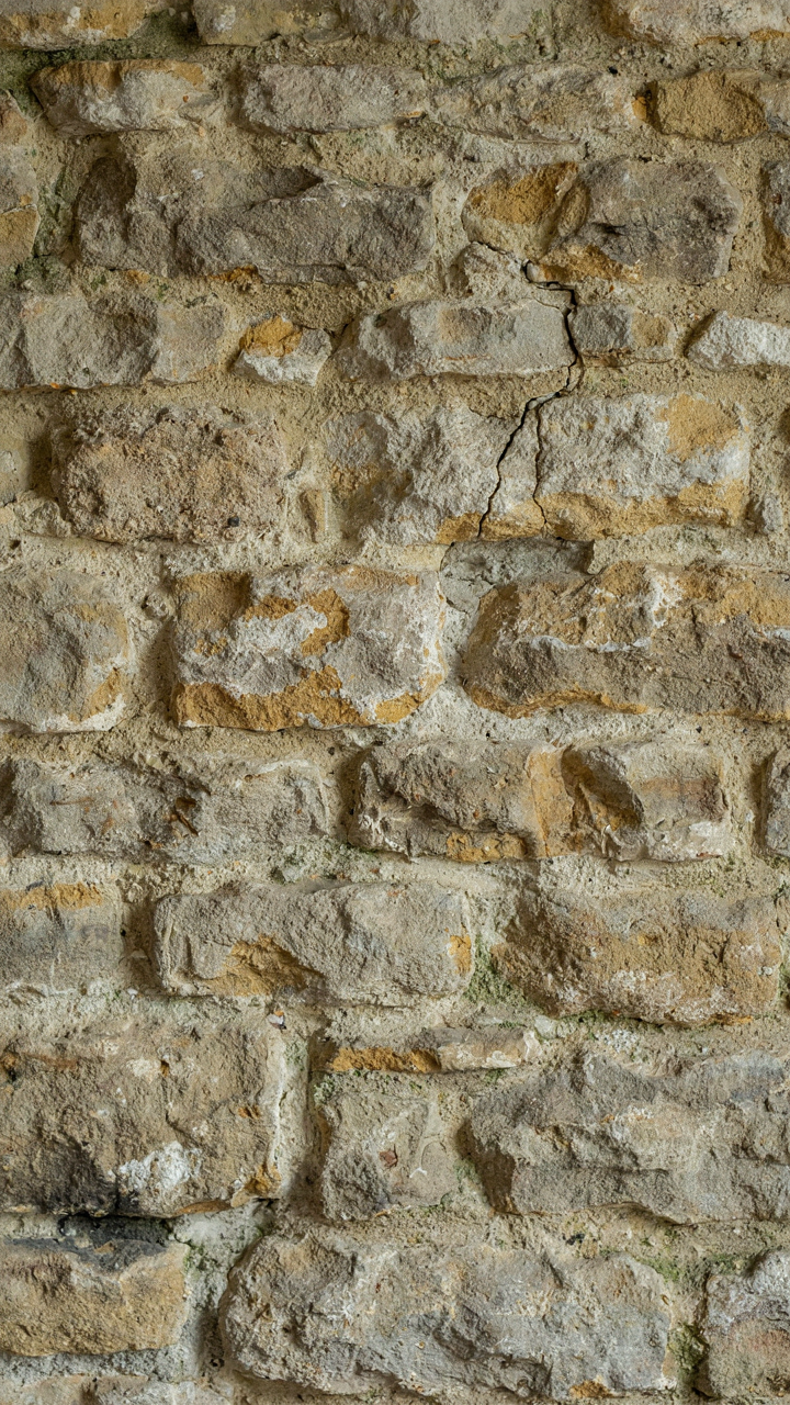 Authentic fieldstone and lime mortar on a cottage fireplace wall, showing texture.