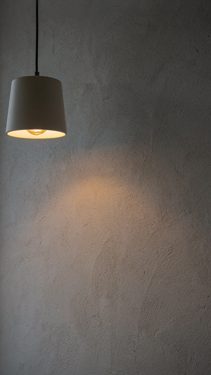 A simple ceramic light fixture with a warm bulb illuminates a textured wall, showing effective