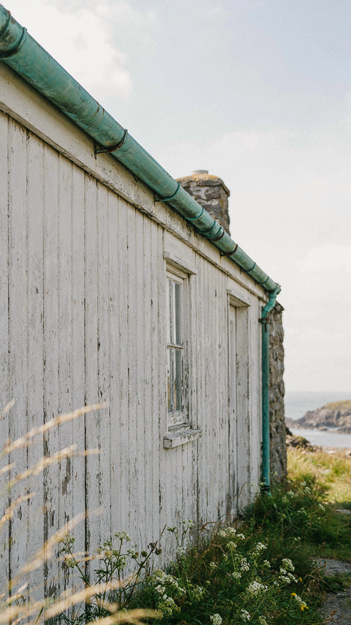 Copper gutter on a fisherman cottage, showing a vibrant green verdigris patina.