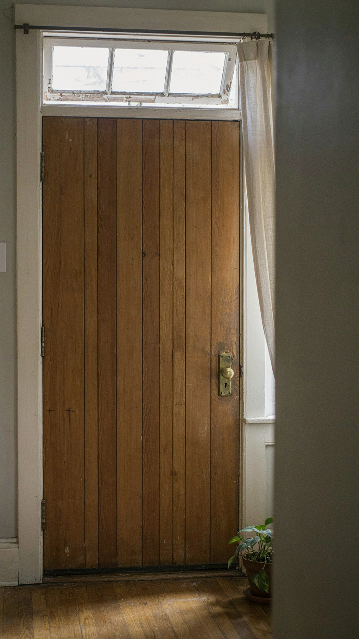 An open transom window sits above a door in a craftsman bungalow.