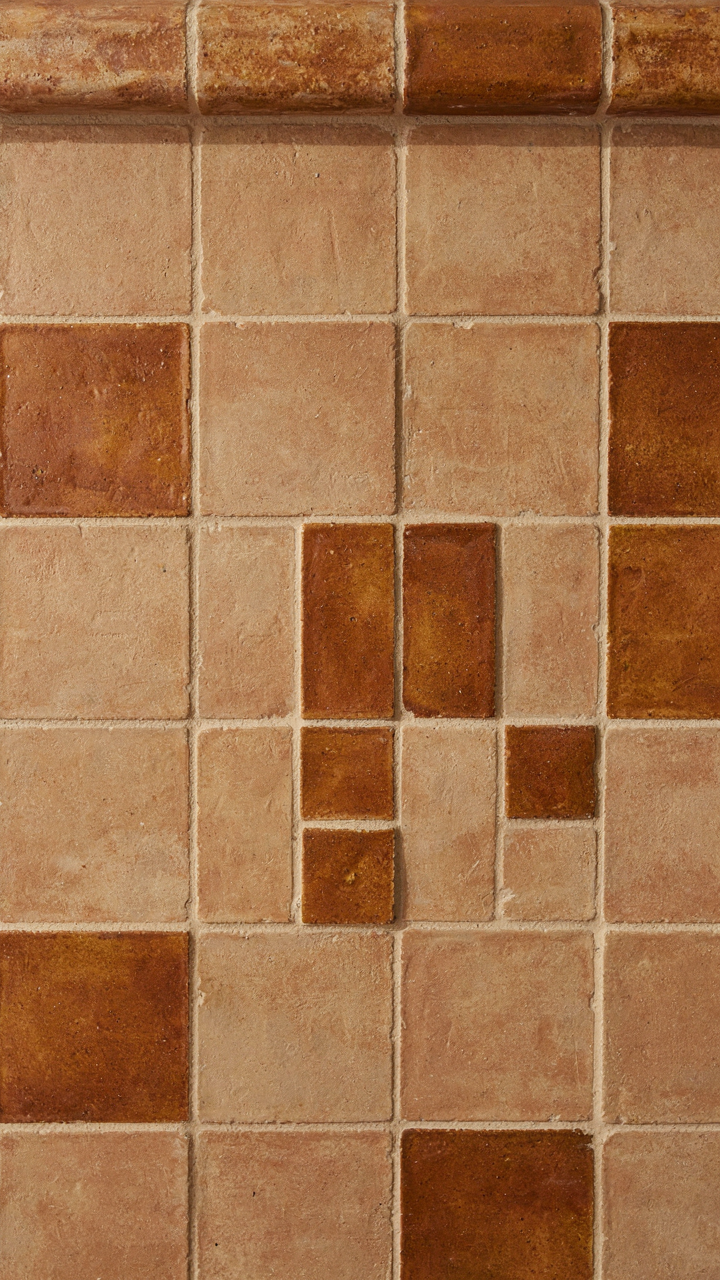Close-up of earth-toned craftsman fireplace tiles with varied textures.