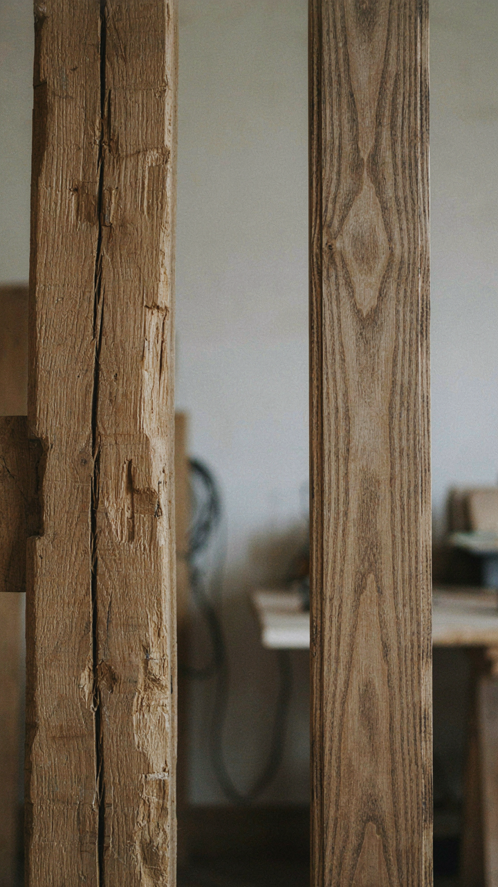 A hand-hewn wood beam with tool marks next to a fake distressed furniture piece.