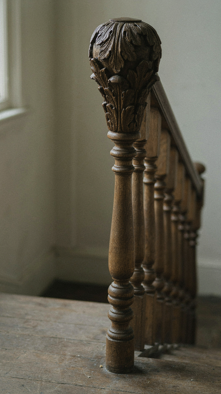 An ornate Victorian newel post with detailed carving at the top, leading to simpler balusters.