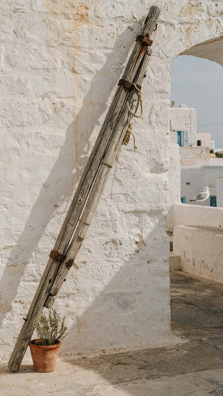 A weathered wooden ship's mast against a whitewashed wall.