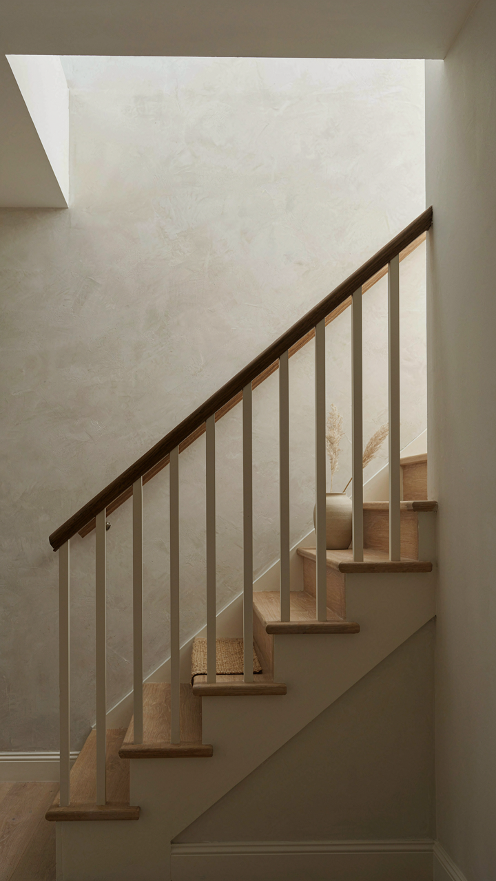 A minimalist cottage staircase with clean lines and a dark handrail.