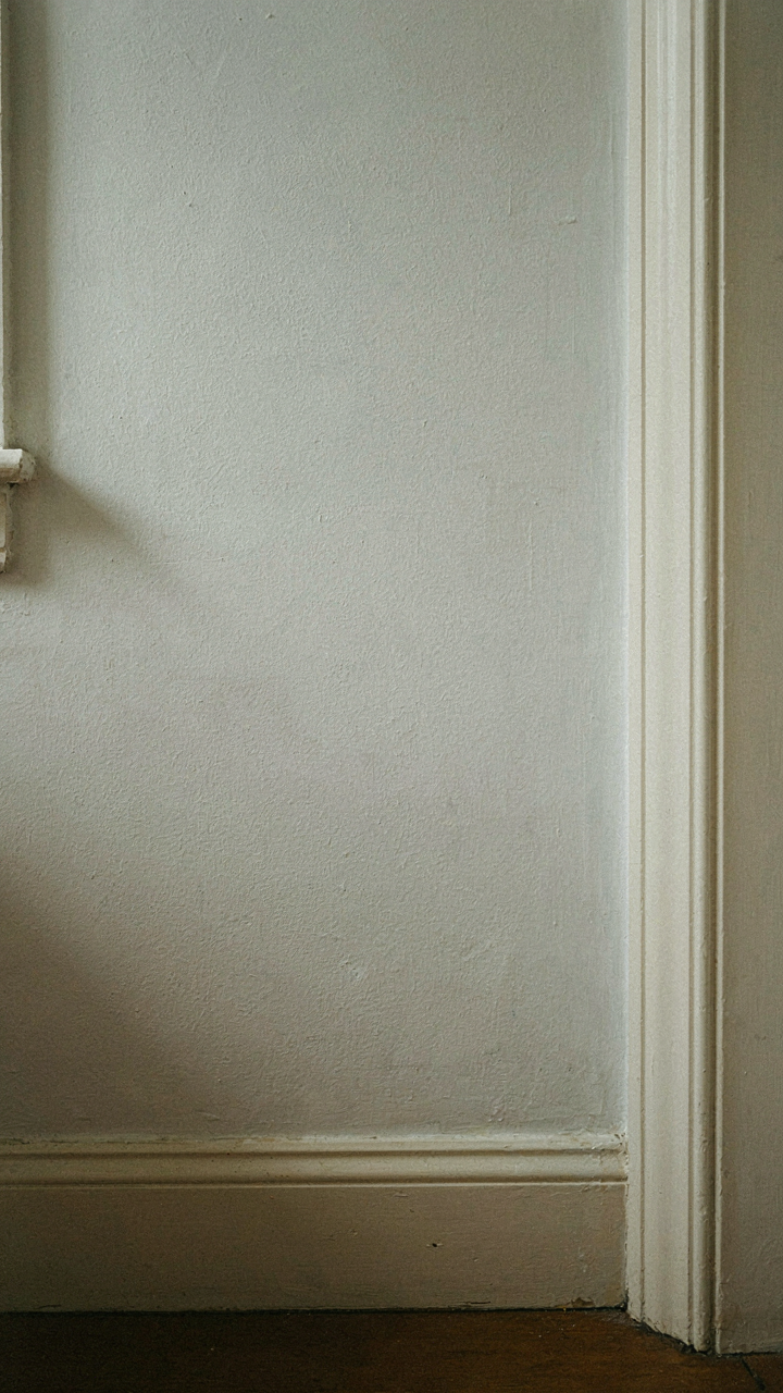 A shadow highlights a door casing in a bright Cape Cod cottage room.