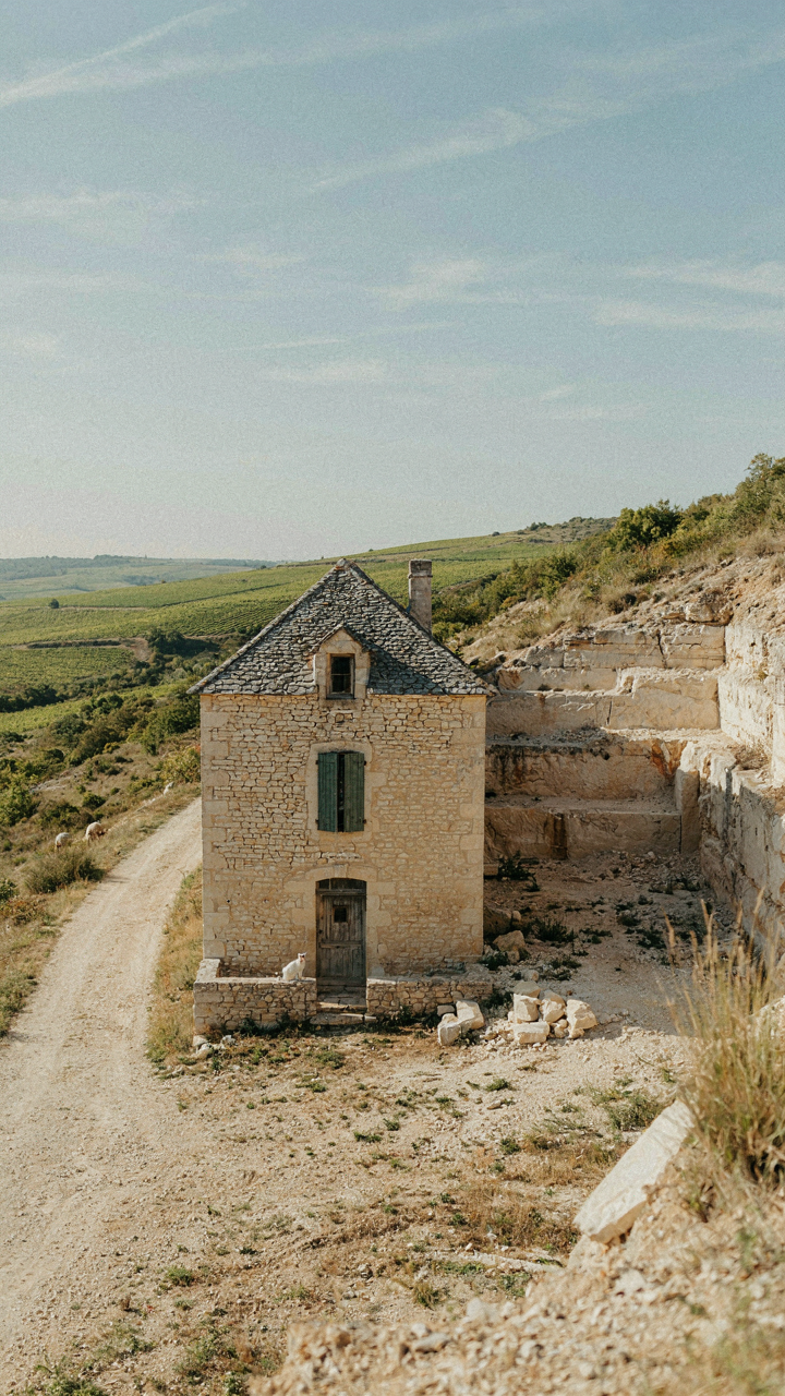 A stone farmhouse is built into a hillside next to a limestone quarry.