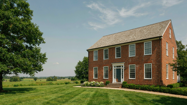 A stately Dutch Colonial house with a distinctive gambrel roof and brick exterior.