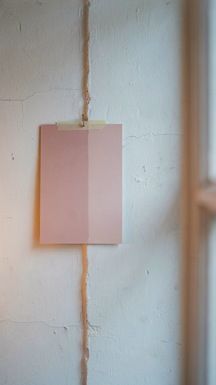 A paint swatch on a wall, lit by warm and cool light sources.