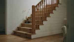 A grand wooden farmhouse staircase curves gracefully in a well-lit, open-concept home.