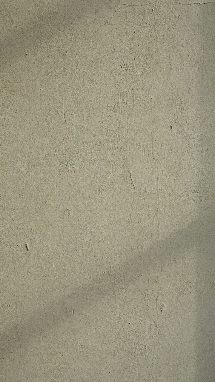 A subtly textured warm off-white farmhouse wall with light highlighting it.