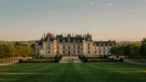 A grand French chateau with turrets stands under a golden sky, surrounded by manicured gardens.