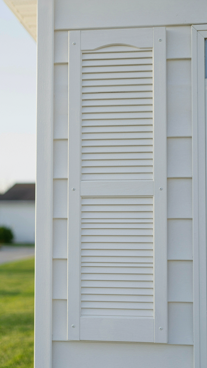 A white vinyl shutter on a vinyl-sided house.