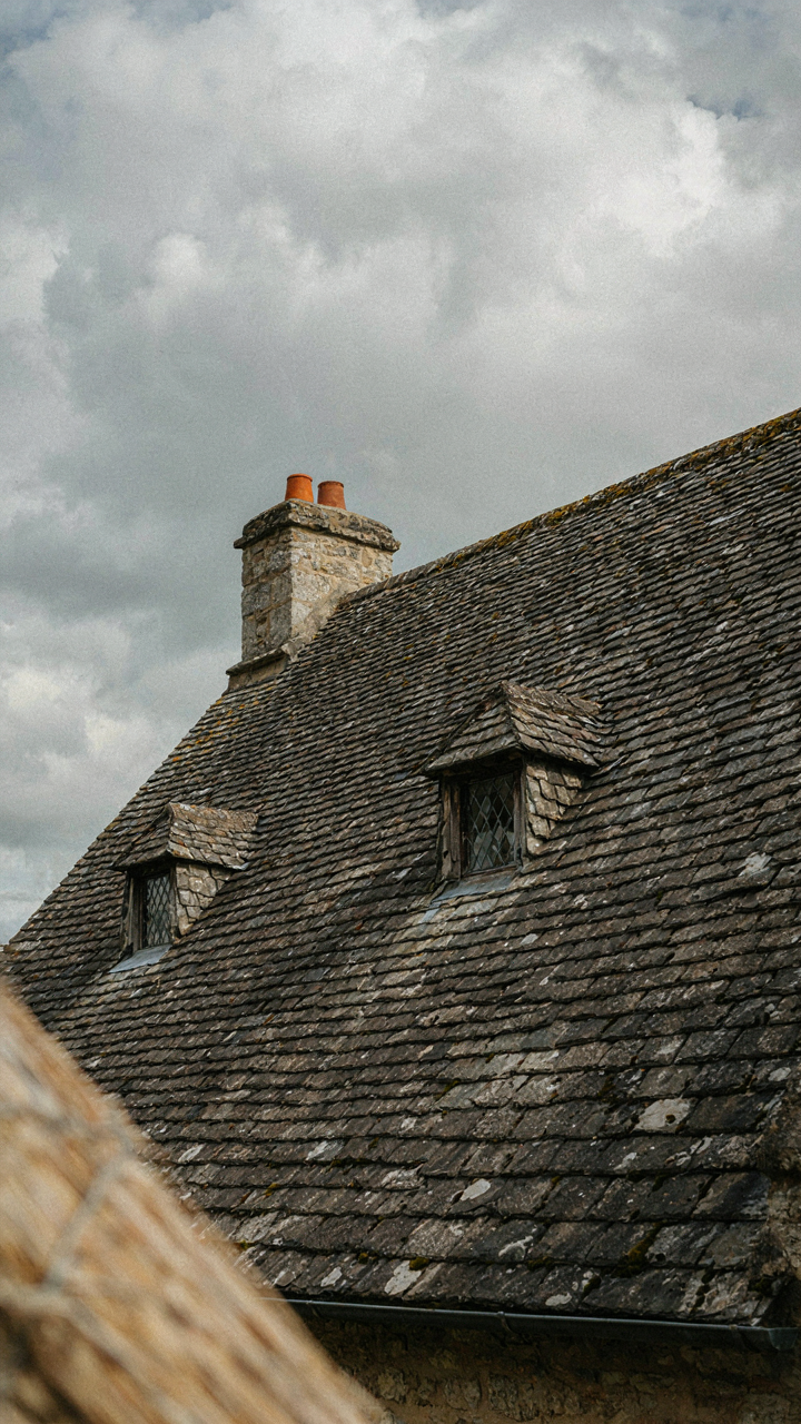 A steep, dark slate roof on a Norman French cottage.
