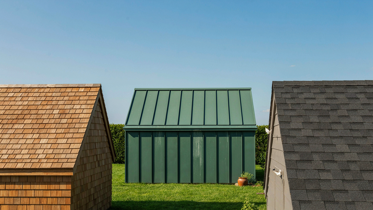 Many different garden shed roofs, including cedar, metal, and asphalt, under a clear sky.