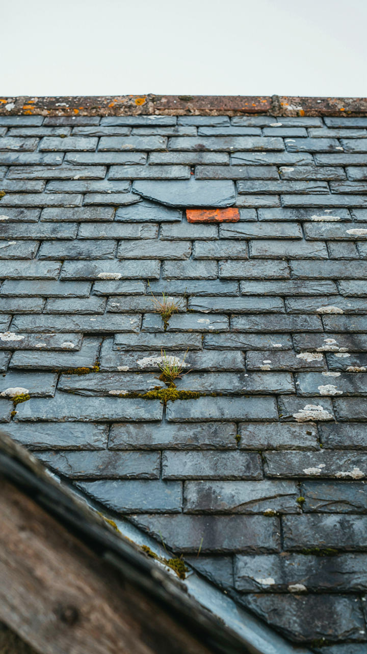 A close up of an old slate roof on a European cottage with repairs.