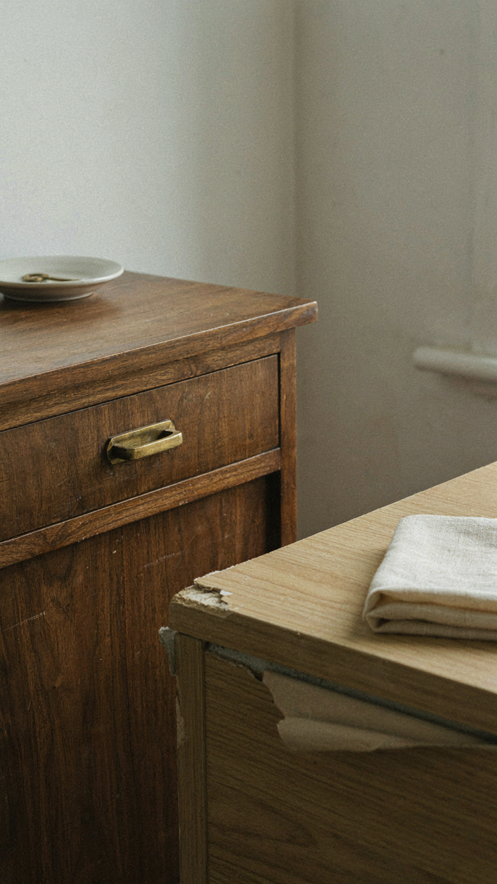 A solid walnut nightstand showing natural grain next to a peeling laminate one.