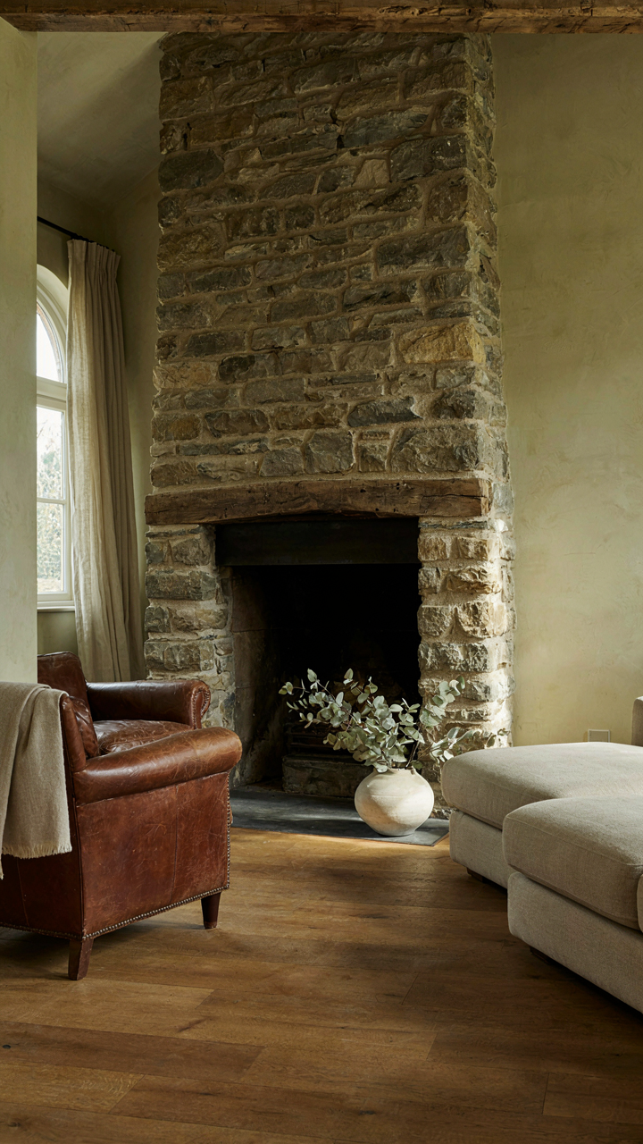 A massive, deep stone fireplace with a timber lintel in a room.