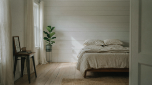 A farmhouse bedroom with white shiplap walls, a wooden bed, and warm sunlight.