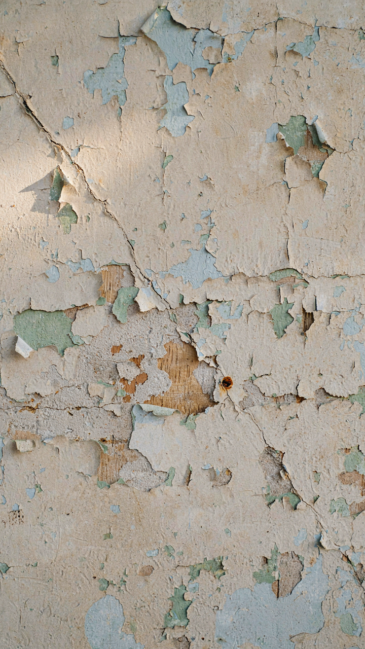 Close up of an old, peeling farmhouse wall with muted, original paint showing.