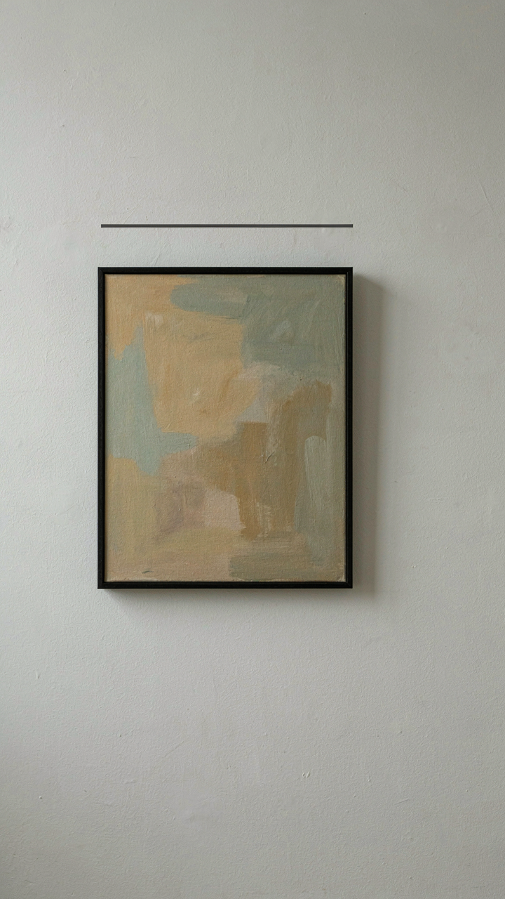 A stark white wall in a coastal bedroom with a single abstract painting.