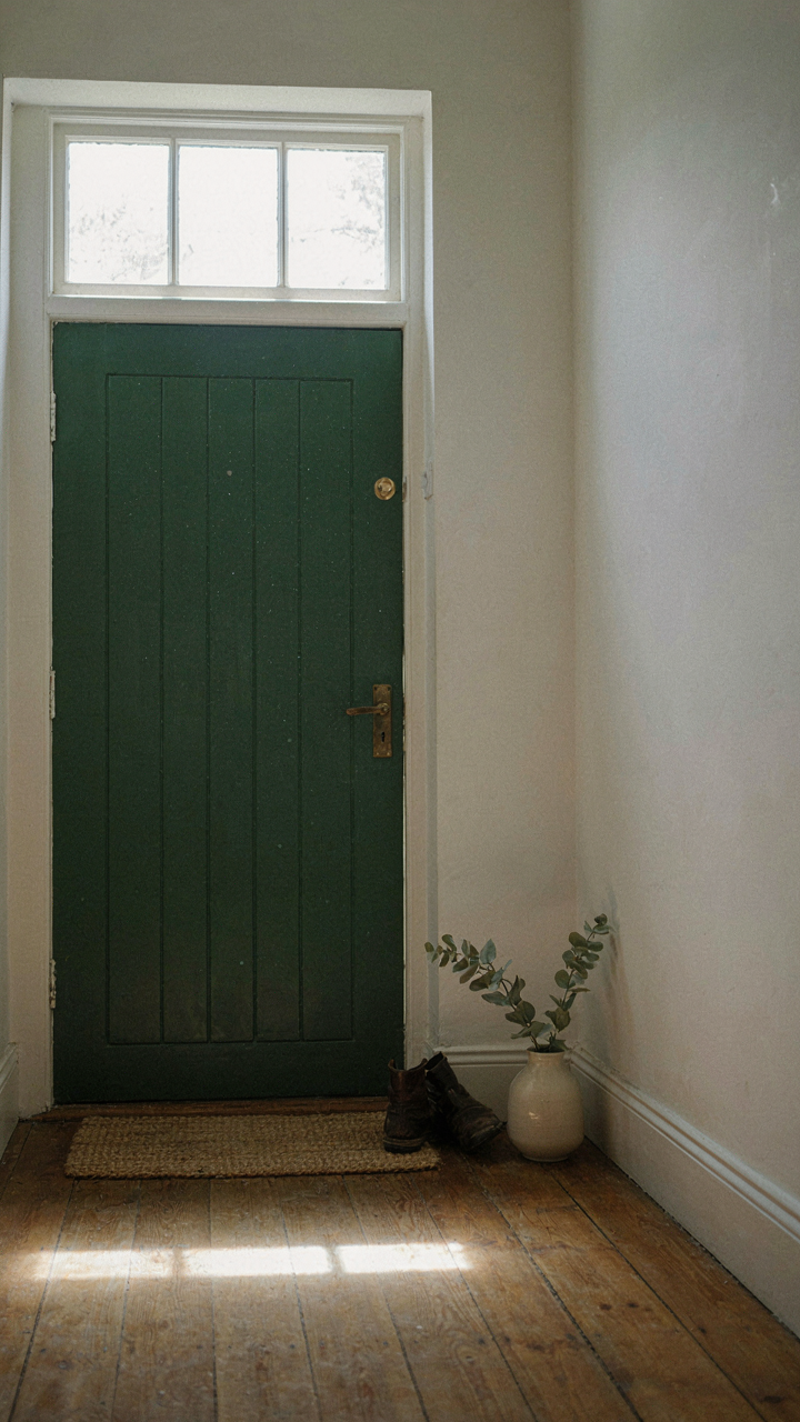 A transom window above an entry door filling a cottage entryway with light.