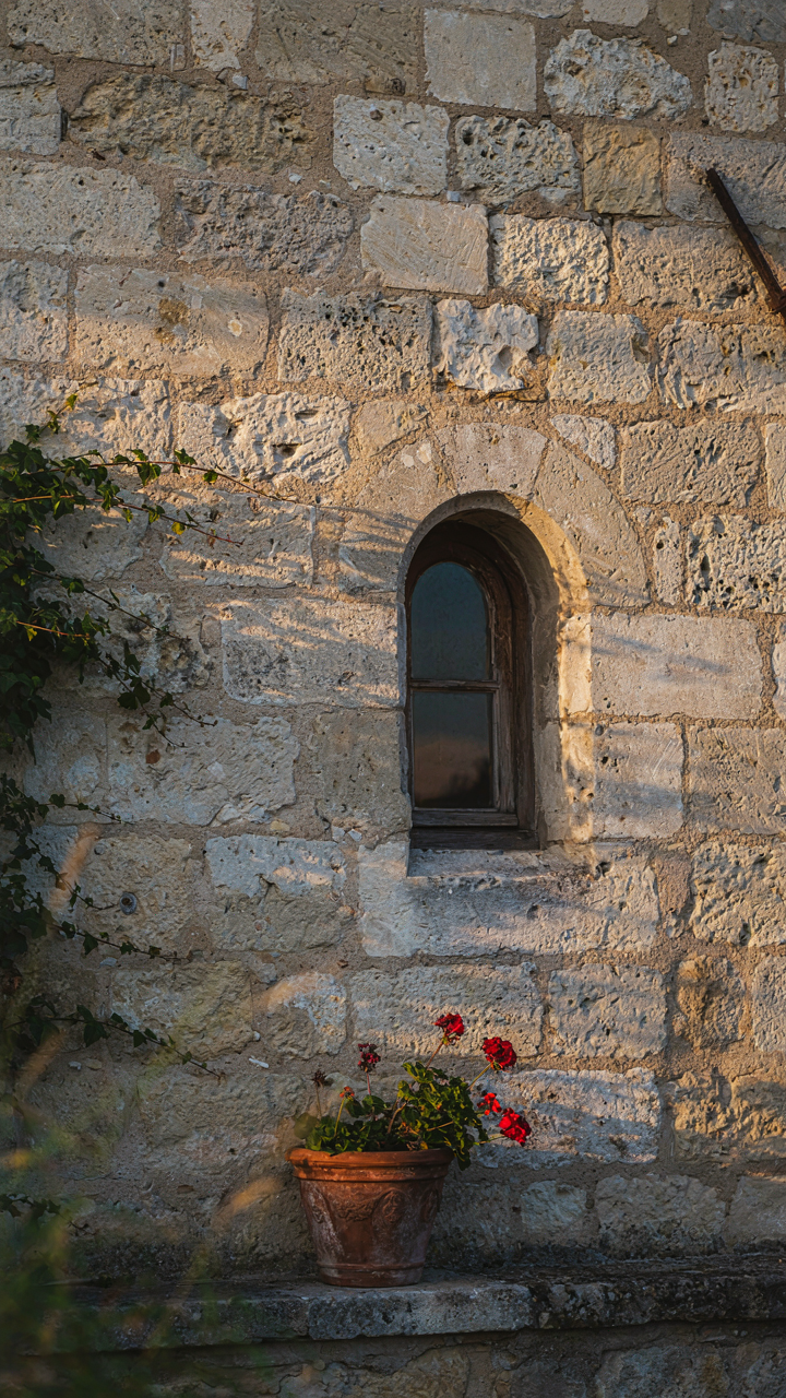 A stone French cottage wall at sunset, highlighted by raking light.